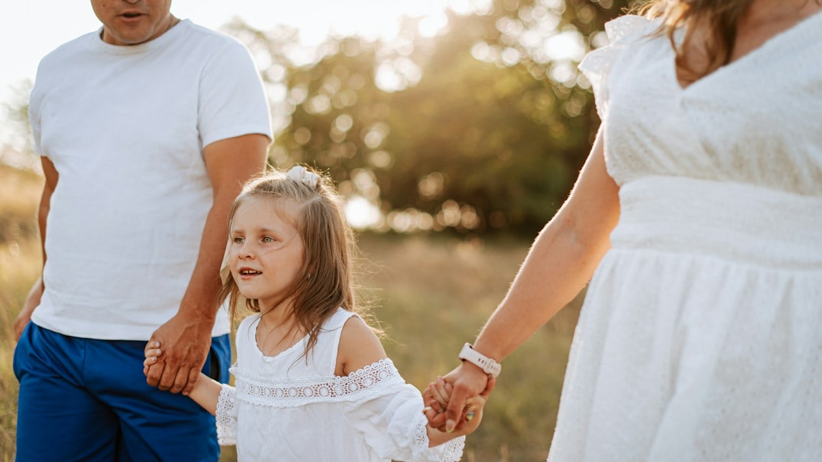 A man and a woman holding hands with a little girl